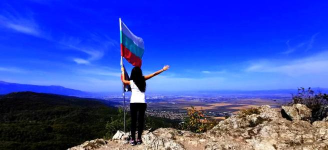 момиче в бяло и черно на връх половрак в лозенската планина, хванало българското знаме